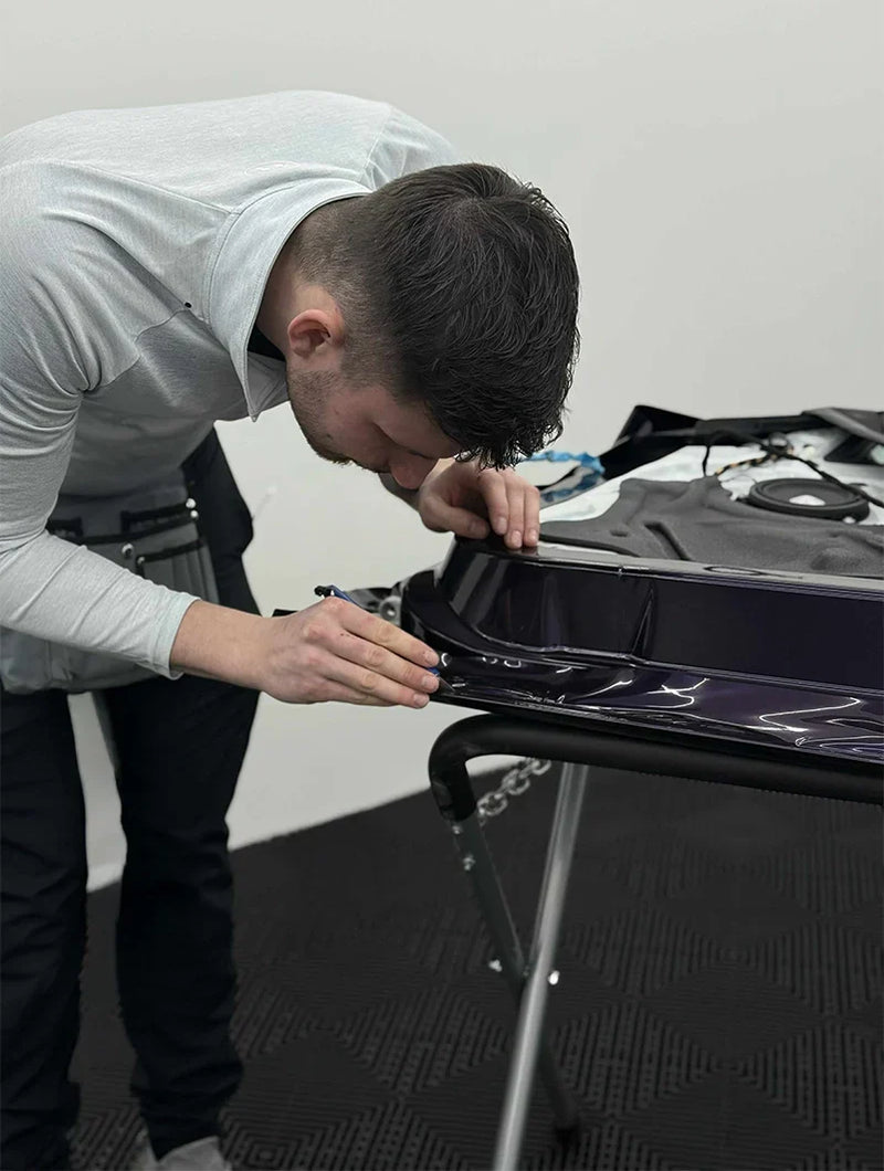 man wrapping car door in purple wrap
